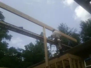 Carpenter setting a ridge beam over a new addition frame — Ice Dam Removal by Roofing Brothers in Clayton